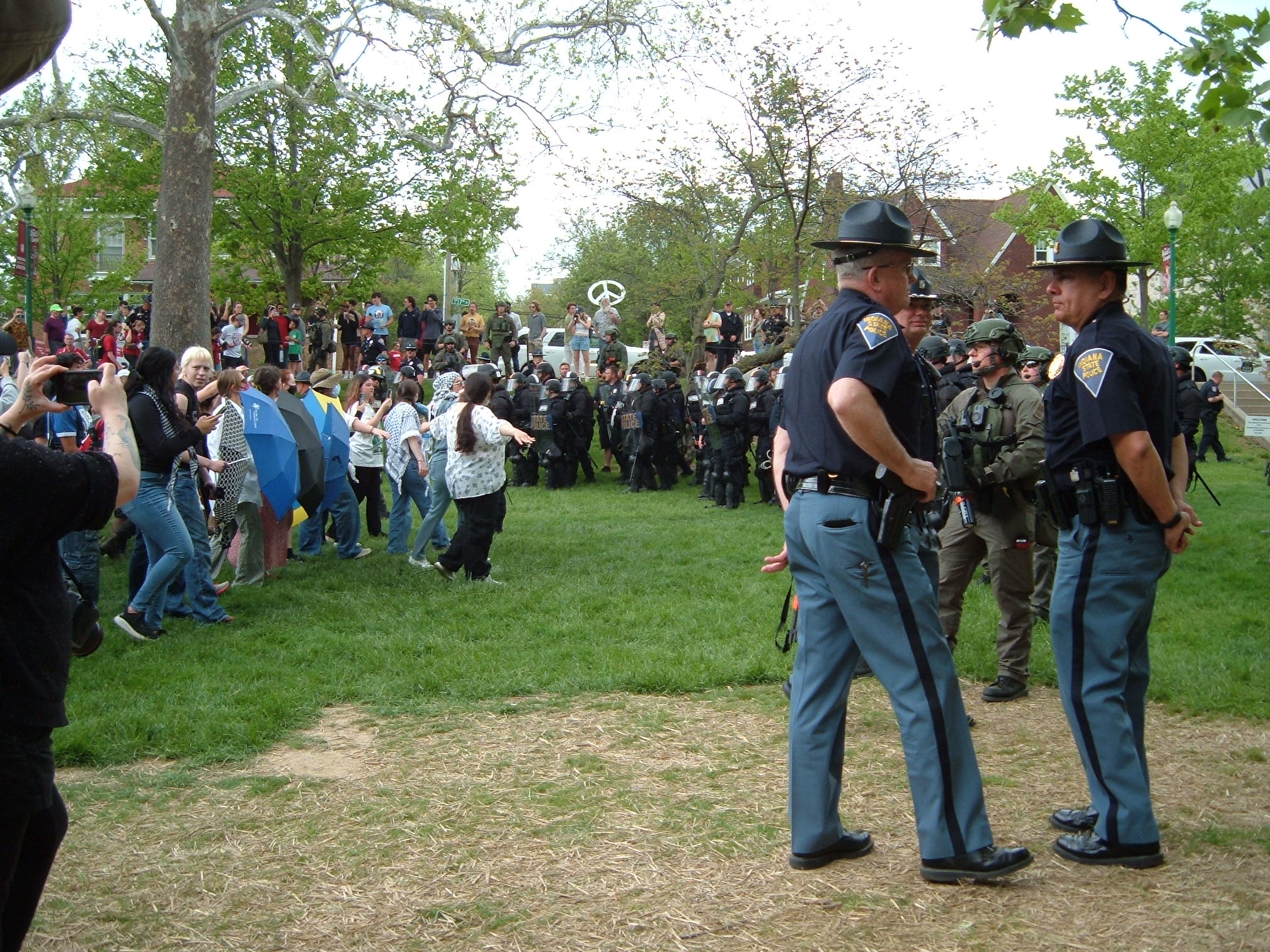 Protestors form a line facing police as they retreat from Dunn Meadow. The commanding officers converse in the foreground as they guide their units away from the scene.